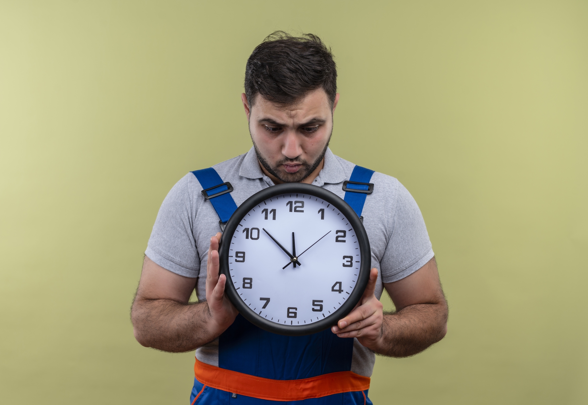 Мужчина в спецодежде смотрит на часы